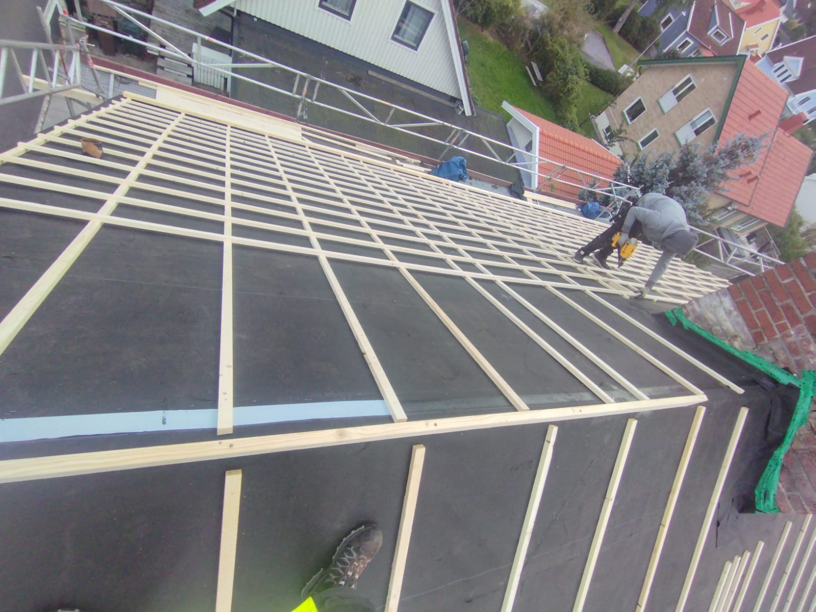 Roof construction with a grid of wooden battens and workers
