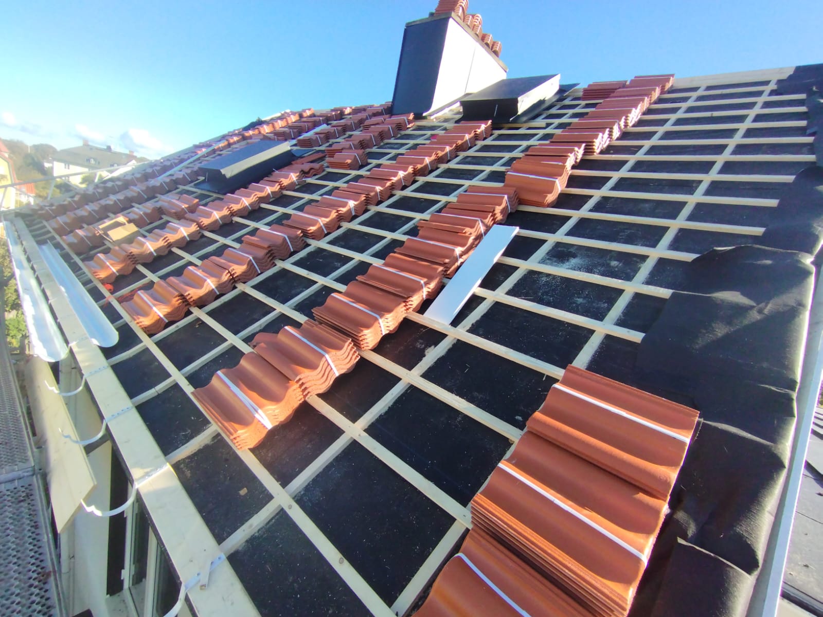 Roof construction site with a worker in a safety vest and hard hat